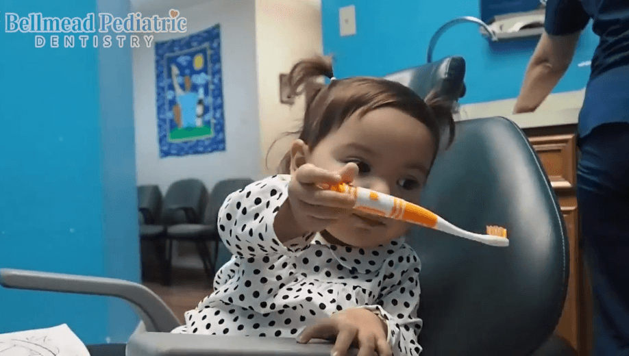 Bellmead Kids Dentistry 3 year old pediatric patient content while sitting in the dentist chair and handing over a tooth brush she is holding 
