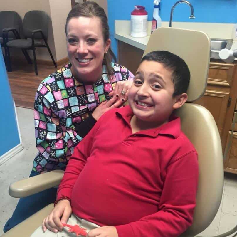 Bellmead Kids Dentistry Dental Hygienist Britany in a treatment room smiling sitting next to a happily smiling pediatric patient sitting in the dentist treatment chair