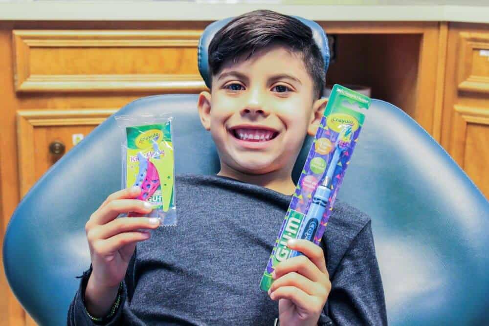 Bellmead Kids Dentistry pediatric patient in the dentist chair showing off the free promotional gifts he received